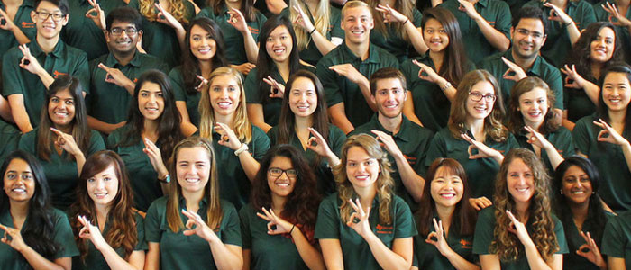 A group of UTD students making the UTD 'Whoosh' hand symbol.